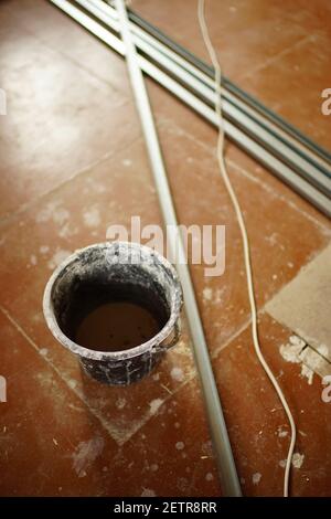 Secchio di plastica nero sporco con gocce sul pavimento marrone Foto Stock