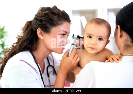 Pediatra che fornisce assistenza sanitaria per il suo bambino paziente in ufficio di una clinica specializzata per bambini Foto Stock