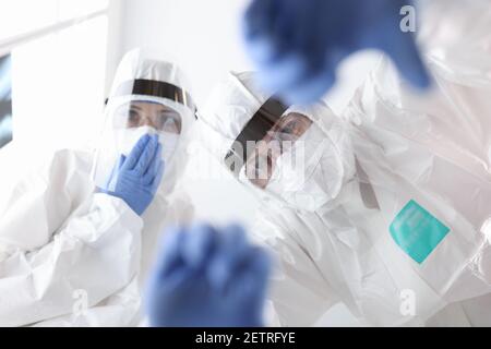 Medici in tute antiplague protettivo aiutare il paziente Foto Stock