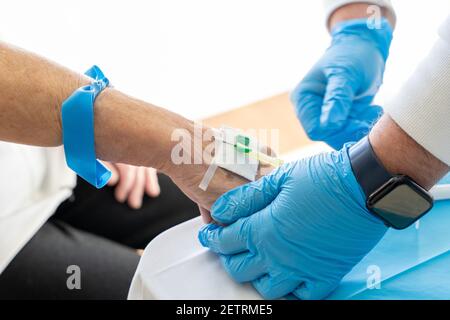 Alto angolo di raccolto medico irriconoscibile con ago che prende sangue campione da paziente senior Foto Stock