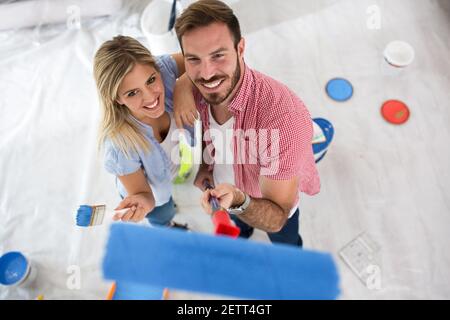 Attraente giovane coppia sorridente che dipinge la loro nuova casa Foto Stock