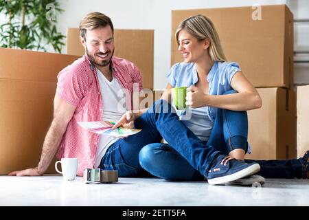 Felice giovane coppia che si muove in nuove scatole di disimballaggio casa e. scelta del colore per la camera da letto Foto Stock