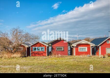 Rosso, sommarstuga tradizionale svedese (case estive) in un villaggio di mare. La stuga scandinava in fila al mare rappresenta il concetto di mysig o hygge Foto Stock