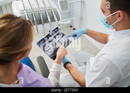 Dentista che mostra un problema del dente su raggi X. Foto Stock