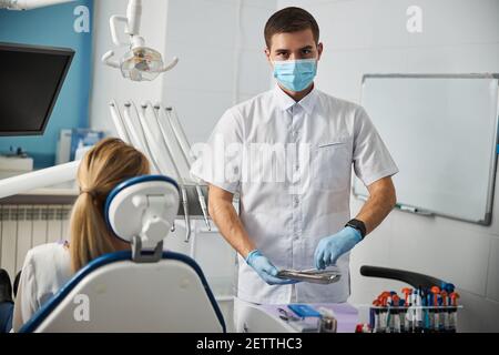 Pinzette per il prelievo di dentisti qualificati da un contenitore in metallo Foto Stock