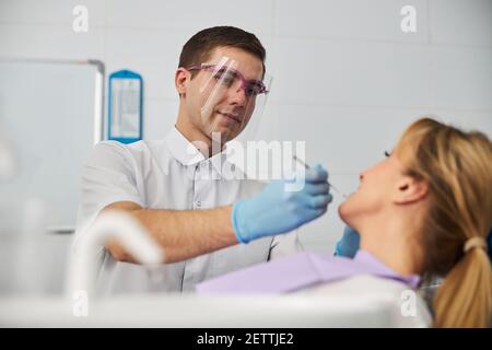 Raccolto dentista professionale utilizzando bocca specchio su donna Foto Stock