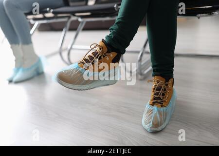 Donne che si siedono in linea con copriscarpe sui loro piedi primo piano Foto Stock