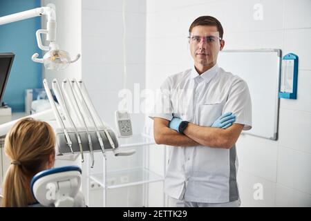 Chirurgo dentale in piedi con braccia incrociate nel suo ufficio Foto Stock