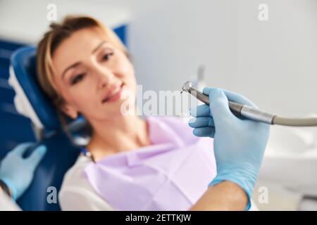Specialista medico che porta la macchina perforatrice al viso della donna Foto Stock
