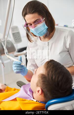 Dentista femminile che usa il cuoio capelluto dentale su un uomo Foto Stock