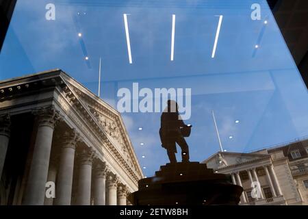 Giorni prima che il Cancelliere Rishi Sunak consegnasse il suo Budget, Royal Exchage (a sinistra) e la Bank of England (a destra) si vedono riflesse nella finestra di un ufficio insieme alla statua dell'ingegnere civile James Henry Greathead, il 1 marzo 2021, a Londra, Inghilterra. James Henry Greathead (1844 – 1896), rinomato per il suo lavoro sulla metropolitana di Londra. Foto Stock