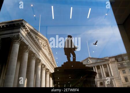 Giorni prima che il Cancelliere Rishi Sunak consegnasse il suo Budget, Royal Exchage (a sinistra) e la Bank of England (a destra) si vedono riflesse nella finestra di un ufficio insieme alla statua dell'ingegnere civile James Henry Greathead, il 1 marzo 2021, a Londra, Inghilterra. James Henry Greathead (1844 – 1896), rinomato per il suo lavoro sulla metropolitana di Londra. Foto Stock