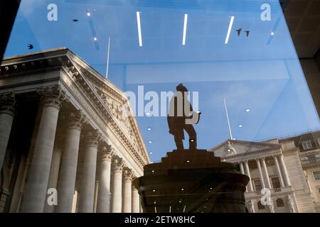 Giorni prima che il Cancelliere Rishi Sunak consegnasse il suo Budget, Royal Exchage (a sinistra) e la Bank of England (a destra) si vedono riflesse nella finestra di un ufficio insieme alla statua dell'ingegnere civile James Henry Greathead, il 1 marzo 2021, a Londra, Inghilterra. James Henry Greathead (1844 – 1896), rinomato per il suo lavoro sulla metropolitana di Londra. Foto Stock