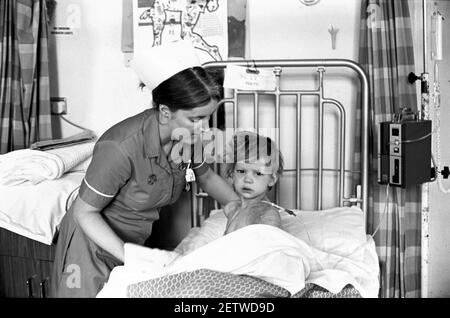 Ospedale Ward Cardiff per bambini. Infermiera che conforta il bambino dopo l'intervento chirurgico Foto Stock