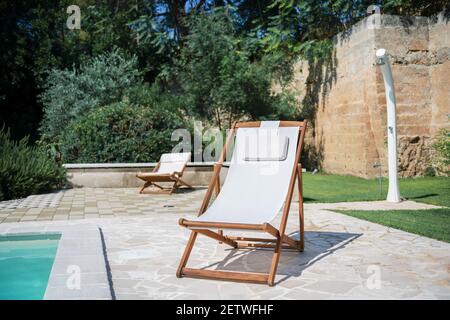 Piscina con acqua blu limpida e due lettini per il sole nella giornata di sole in un cortile, bella vacanza per il relax e lo svago, concetto di consapevolezza ben bei Foto Stock