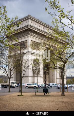 Un uomo si siede su una panchina nella piazza dentro Di fronte all'Arco di Trionfo a Parigi Foto Stock