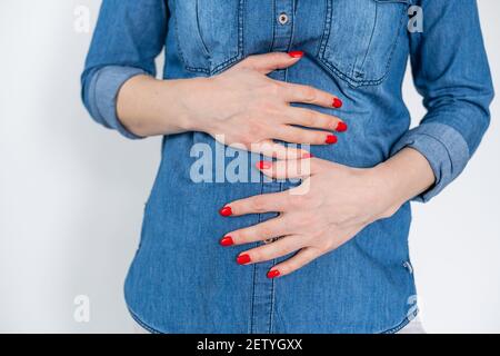 Giovane femmina che tocca lo stomaco nel dolore . Infiammazione renale e terapia. Medicina e sanità concetto. Sfondo bianco Foto Stock