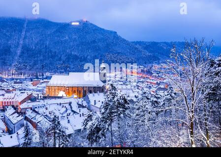 Brasov, Transilvania. Paesaggio notturno invernale con la Chiesa Nera e Carpazi Montagne, viaggio invernale in Romania. Foto Stock