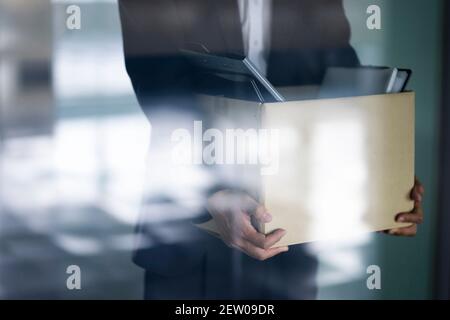 Infornato businessman che trasporta la scatola degli articoli personali Foto Stock