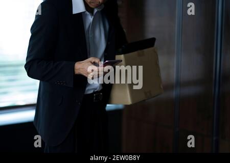 Infornato uomo d'affari utilizzando smartphone con scatola di appartiene Foto Stock