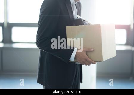 Infornato businessman che trasporta la scatola degli articoli personali Foto Stock