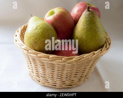 Un cesto di vimini pieno di mele e pere Foto Stock