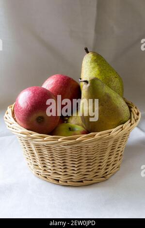 Un cesto di vimini pieno di mele e pere Foto Stock