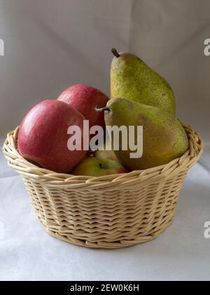 Un cesto di vimini pieno di mele e pere Foto Stock