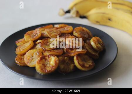 Fette di plantare caramellate. Uno spuntino tradizionale a base di tè del Kerala. Tagliare la plantare matura a fette e tostarla in una padella aggiungendo del ghee n un po' di sug marrone Foto Stock