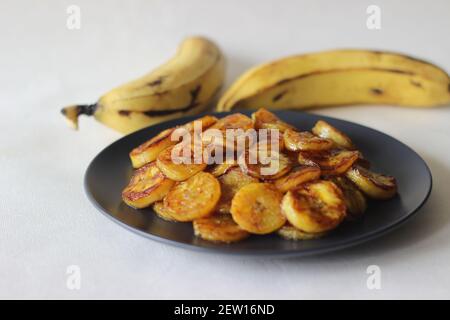 Fette di plantare caramellate. Uno spuntino tradizionale a base di tè del Kerala. Tagliare la plantare matura a fette e tostarla in una padella aggiungendo del ghee n un po' di sug marrone Foto Stock