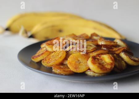 Fette di plantare caramellate. Uno spuntino tradizionale a base di tè del Kerala. Tagliare la plantare matura a fette e tostarla in una padella aggiungendo del ghee n un po' di sug marrone Foto Stock