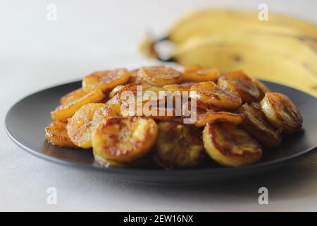 Fette di plantare caramellate. Uno spuntino tradizionale a base di tè del Kerala. Tagliare la plantare matura a fette e tostarla in una padella aggiungendo del ghee n un po' di sug marrone Foto Stock