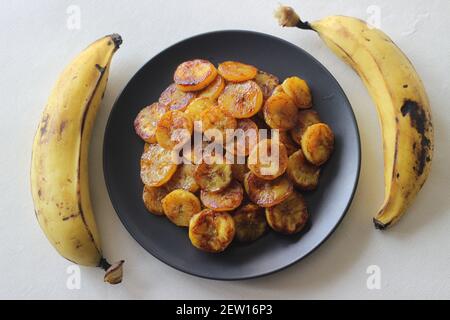 Fette di plantare caramellate. Uno spuntino tradizionale a base di tè del Kerala. Tagliare la plantare matura a fette e tostarla in una padella aggiungendo del ghee n un po' di sug marrone Foto Stock