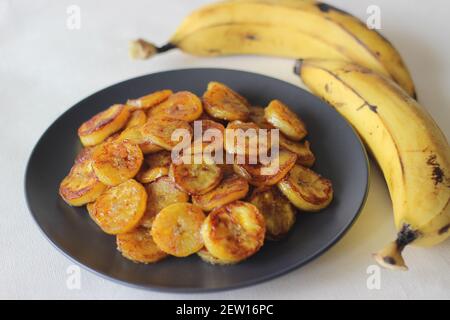 Fette di plantare caramellate. Uno spuntino tradizionale a base di tè del Kerala. Tagliare la plantare matura a fette e tostarla in una padella aggiungendo del ghee n un po' di sug marrone Foto Stock