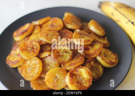 Fette di plantare caramellate. Uno spuntino tradizionale a base di tè del Kerala. Tagliare la plantare matura a fette e tostarla in una padella aggiungendo del ghee n un po' di sug marrone Foto Stock