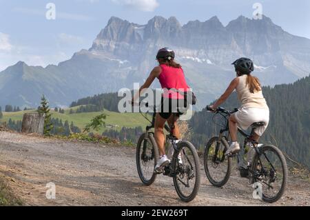 Svizzera, Canton Vallese, Morgins, giovani donne in mountain bike elettriche, con i Dents du Midi (3257m) sullo sfondo Foto Stock