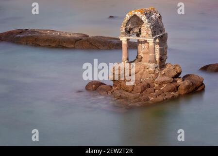 Statua di Saint Guirec in alta marea sulla spiaggia di Ploumanach in Perros-Guirec, Côtes d'Armor, Bretagna, Francia Foto Stock