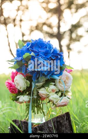 Bouquet di nozze in un vaso d'acqua nella foresta su un moncone Foto Stock