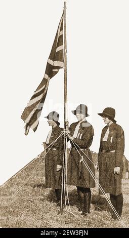 Una prima fotografia da stampa (circa 1940) di tre guide britanniche che fungono da festa a colori in un campo di Girl Guide in Gran Bretagna. Foto Stock