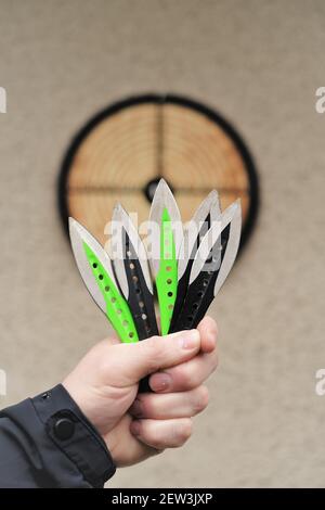 Lancio di coltelli. Sport e hobby . Lancio di coltelli in un primo piano della mano di un uomo e un bersaglio sul wall.Outdoor sport. Raggiungimento degli obiettivi Foto Stock