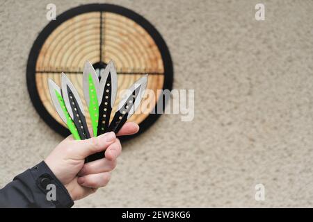 Lancio di coltelli. Sport e hobby . Lancio di coltelli in un primo piano della mano di un uomo e un bersaglio sul wall.Outdoor sport. Concetto di raggiungimento degli obiettivi. Foto Stock