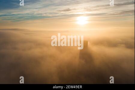 Sole incandescente al mattino presto sopra i grattacieli degli edifici della città durante il tempo pesante nebbia nebbiosa, povero paesaggio urbano sopra la vista. La Manga del Mar Menor s Foto Stock