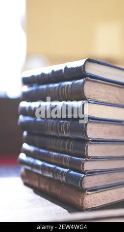 diversi libri vecchi e leggermente usurati accatastati in una torre su una scrivania Foto Stock