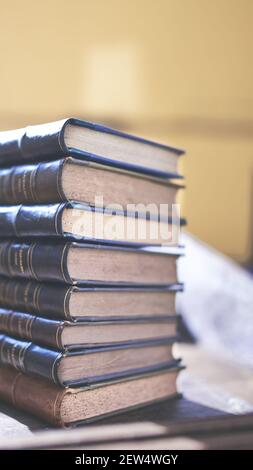 diversi libri vecchi e leggermente usurati accatastati in una torre su una scrivania Foto Stock