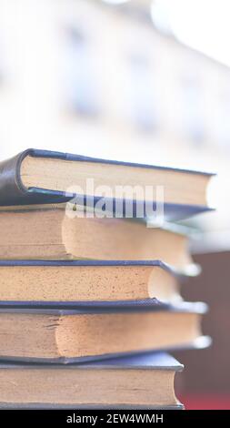 diversi libri vecchi e leggermente usurati accatastati in una torre su una scrivania Foto Stock