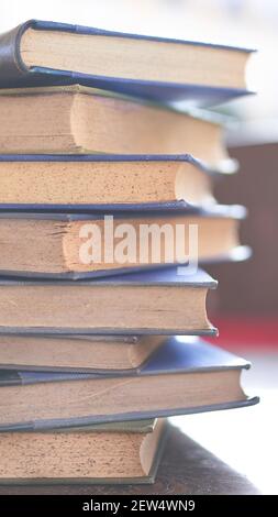 diversi libri vecchi e leggermente usurati accatastati in una torre su una scrivania Foto Stock