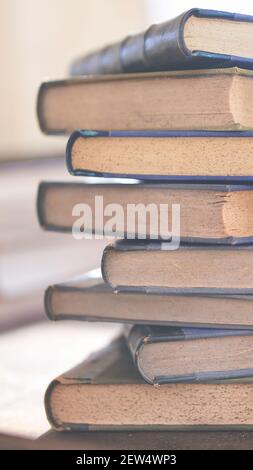 diversi libri vecchi e leggermente usurati accatastati in una torre su una scrivania Foto Stock