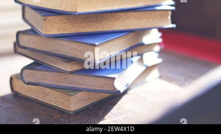 diversi libri vecchi e leggermente usurati accatastati in una torre su una scrivania Foto Stock