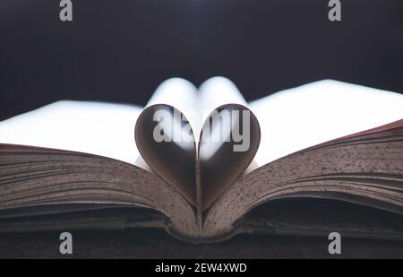 Apri il libro con le pagine piegate a forma di cuore su una scrivania di legno. Foto Stock