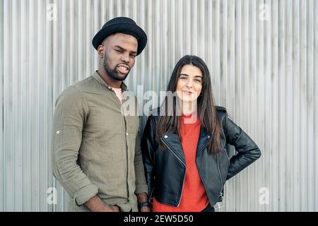 Coppia di etnicità mista alla moda che pende l'una sull'altra Foto Stock